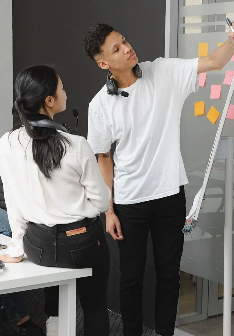付箋を貼ったボードの前で話し合う二人(イメージ写真)